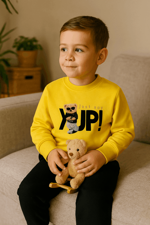 Αγόρι με σετ φόρμες, μπλούζα κίτρινη με στάμπα Yup και μαύρο παντελόνι φόρμα και παιχνίδι αρκουδάκι στο χέρι